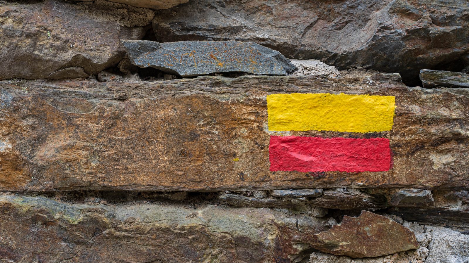 A red and yellow painted waymark on a rock face