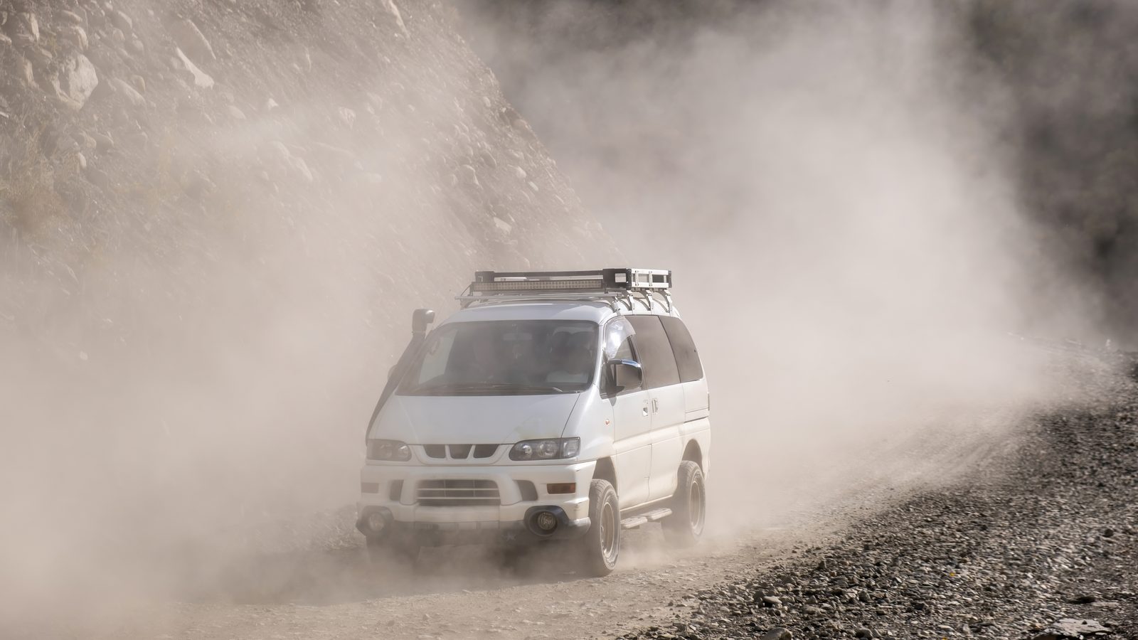 A four-wheel-drive minibus on a dusty unpaved road